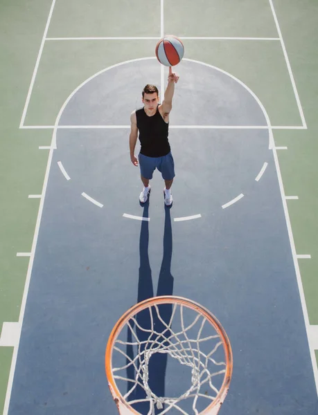 Basketbal pouliční hráč s basketbalem venkovní. Ručně točící se koš. Vyrovnávací basketbal na prstu. — Stock fotografie
