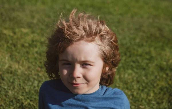 Vicces gyerek arc közelről. Gyerekek a füvön a park fején portré. — Stock Fotó