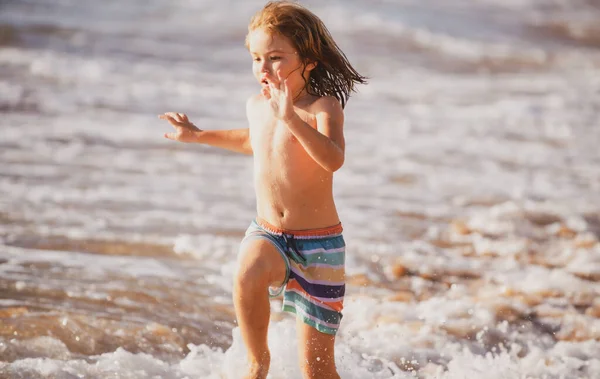 Un ragazzino che corre sulla spiaggia. Bambino felice correre in mare in vacanza estiva. Viaggi e avventure in mare o in mare. — Foto Stock