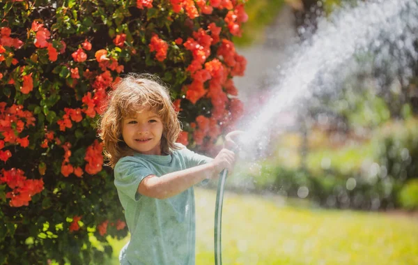 뒷마당에 정원 호스갖고 놀고 있는 재밌는 꼬마 애. 아이들은 자연 속에서 물보라를 튀기는 것을 즐긴다. 야외 활동을 하는 여름 아이들. — 스톡 사진