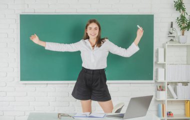 Kız öğrenci, lisede ya da üniversitede tebeşirle tebeşirle elini kaldırmış, heyecanlı amazet öğrencisini karatahta üzerine oturtmuş..