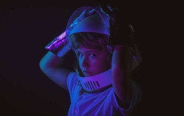 Kapalı çocuk portresi siyah, macera hayalinde izole edilmiş. Çocuk astronotla astronotçuluk oynuyor..