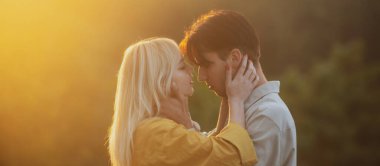 Sarılıp kucaklaşan genç aşıklar. Şehvetli aşıklar gün batımında sarılıp öpüşüyorlar. Sevgi ve şefkat dolu bir çift..