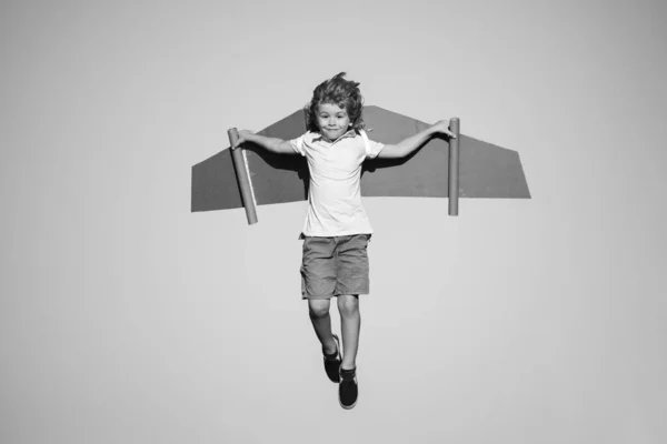 Дети летают. Смешной мальчик летит с игрушечными крыльями картонного самолета на голубом небе, скопировать пространство. Запускай концепцию свободы, беззаботный ребенок. — стоковое фото