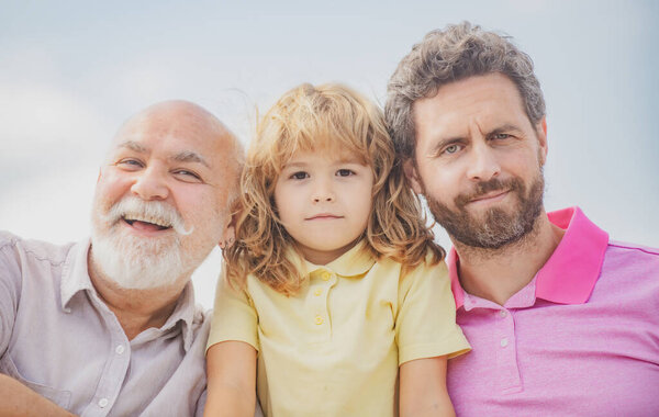 Мальчик-сын с отцом и дедушкой, портрет на открытом воздухе. День Отцов. Мужчины разного возраста.