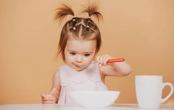 Portret van een schattig blank kind met lepel. Hongerige rommelige baby met bord na het eten van puree. Babyvoeding voor kinderen. — Stockfoto