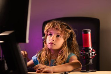 Geceleri bilgisayar kullanan bir çocuk. Karanlık bir odada bilgisayarı olan bir çocuk. Okul, eğitim, online öğrenme konsepti. Klavyede yazan öğrenci..