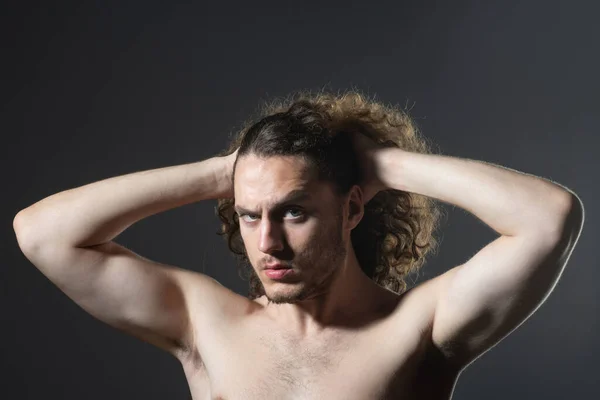 Homem com cabelo encaracolado. Cabelo encaracolado saudável, close up retrato de atraente masculino bonito macho brutal cara com longo encaracolado isolado em fundo cinza. Mans corte de cabelo moderno. — Fotografia de Stock