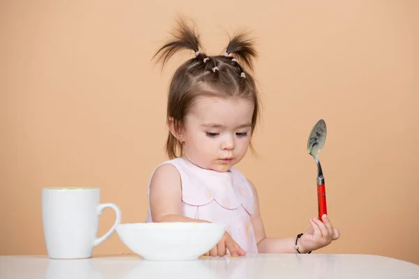 Nourriture pour bébé, bébés mangeant. Portrait de mignon enfant caucasien avec cuillère. Bébé affamé avec assiette après avoir mangé de la purée. — Photo