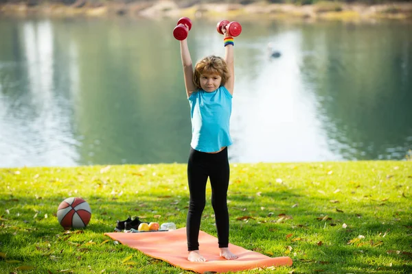 Niños deportistas. Niños ejercitando pesas de fitness. Fuerte niño haciendo ejercicio con la mancuerna en el parque al aire libre. —  Fotos de Stock