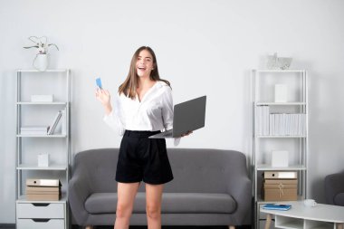 Dizüstü bilgisayarı ve kredi kartı olan genç bir iş kadını. Mali planlama.