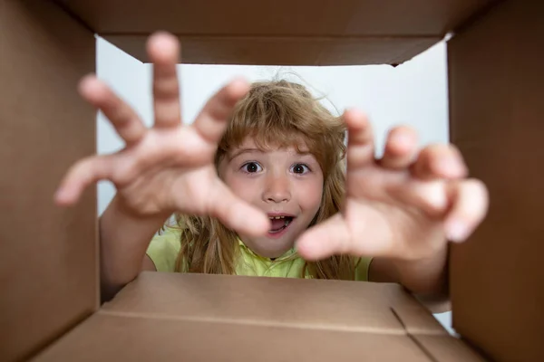 Amazed surprised shocked little boy peeking inside gift box, unpacking present with funny astonished expression, impatient child unboxing surprise. Children expression surprised face. — Stock Photo, Image