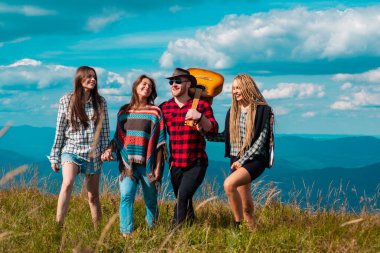Bir grup arkadaş yaz günü kır yürüyüşü yapıyor. Gençler kırsalda yürüyüş yapıyor, yaz tatilinde açık havada. Yaz festivalinde bir grup genç.
