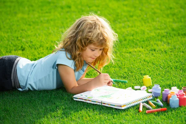 Kinder malen Zeichenkunst. Porträt eines lächelnden glücklichen Kindes, das Kunst und Handwerk im Hinterhof oder Frühlingspark genießt. Kinder zeichnen mit Bleistiften. — Stockfoto