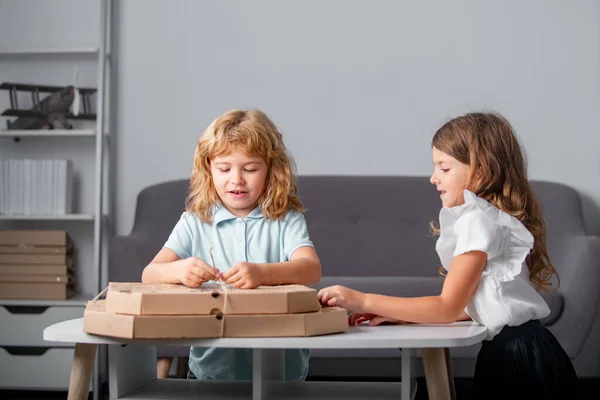 Dzieci otwierają pudełko po pizzy w domu. Zabawne dzieci chłopiec i dziewczyna przygotowuje się do jedzenia pizzy. — Zdjęcie stockowe