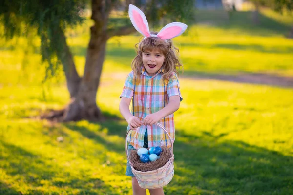 Bunny child. Child boy hunting easter eggs, laying on grass. Kid in rabbit bunny ears outdoor. Easter bunny children. — Stock Photo, Image