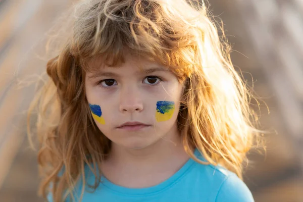 Savaş yok, savaşı durdurun, Rus saldırısını durdurun. Çocukların yanağında Ukrayna bayrağı. Çocuklar yüzünüzü kapatın..