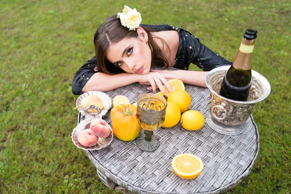 Sexy woman relaxing and eating fruit outdoor. Exotic summer diet, tropical fruits. Top view vegetarian girl enjoy berries fruits vegetable, dinner table on green grass park outside. — Stock Photo, Image