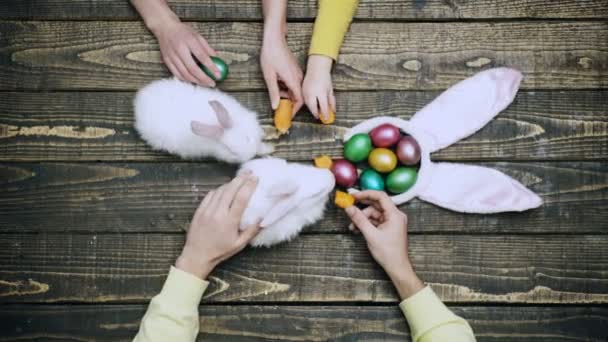 Šťastná rodina se připravuje na Velikonoce. Králík králík a velikonoční vejce dřevěný stůl top. — Stock video