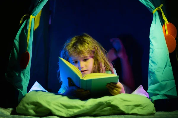 Çocuklar kitap okuyor. Küçük çocuk evde oturup masal kitaplarındaki resimleri izliyor. İlkokul için ödev yapan bir çocuk. Çocuklar çalışır. — Stok fotoğraf