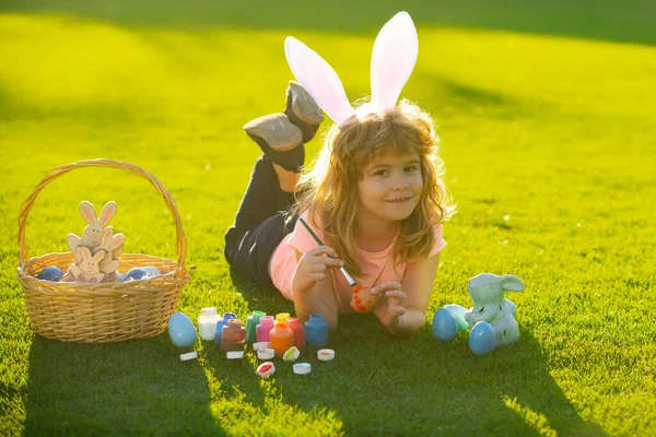 Kind jongen met paaseieren en konijnenoren eieren op gras. — Stockfoto