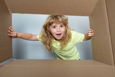 Karton kutulu mutlu çocuk, internet mağazasından paketleri açıyor. Çocuk müşteriler hızlı teslimat hizmetinden memnun. Paketleme veya açma kavramı.