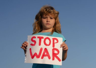 Çocuk bir işaret taşıyor. Savaşı durdurun. Küçük çocuğun portresi savaşı durdurun diyor, yazıyla bayrağı kaldırıyor savaşı durdurun. Ukrayna bayrağı ve poster taşıyan bir çocuk Savaşı durdurun.