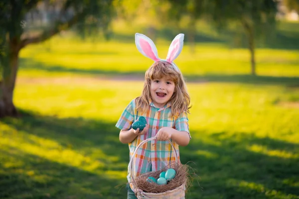 Feliz Páscoa para as crianças. Miúdos a caçar ovos de Páscoa. Criança em orelhas de coelho caçam ovos de Páscoa. — Fotografia de Stock
