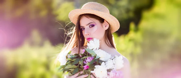 Utomhus mode foto av vackra unga kvinna omgiven av blommor. Sommarmodell med blommor i händerna utomhus. — Stockfoto