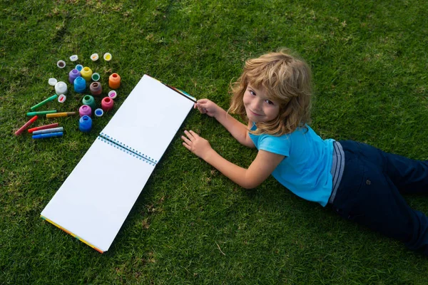 Skolbarn ritar i sommarparken, målar konst. Liten målare ritar bilder utomhus. Barn hobby, lycklig barndom. — Stockfoto