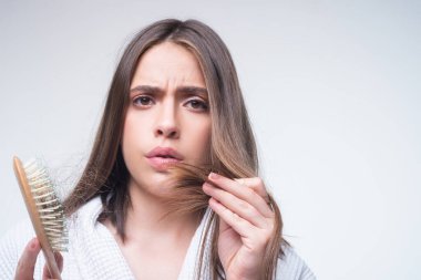 Saç dökülmesi. Kadın saç dökülmesinden rahatsız. Sorunlu saçlı, izole edilmiş üzgün bir kızın portresi. Endişeli kız uzun hasarlı, sağlıksız saçları elinde tutuyor..