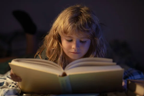 Милый маленький мальчик, читающий книгу. Ребенок с открытой книгой. Уроки домашнего обучения. Сконцентрированный маленький мальчик читает дома книги в постели. Детское развитие воображения. — стоковое фото