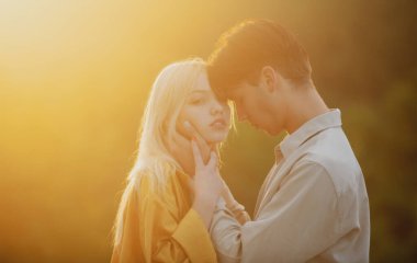 Genç aşık bir çift birlikte zaman geçirir. Gün batımında parkta sarılıp öpüşen iki aşık. Aşk, gençlik, mutluluk konsepti.