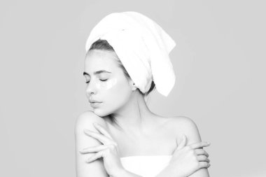 Yüzünde kozmetik krem, cildinde de yumuşaklık var. Vücut bakımı. Tenine krem süren havluyla şehvetli bir kadın. Vücut bakımı ve kaplıca salonu konsepti.
