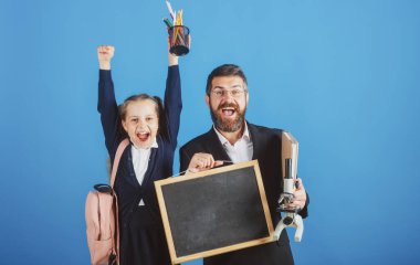 Okuldaki ilk günüm. Baba, öğretmen ve birinci sınıftaki küçük kız. Okula geri dön, üniformalı kız öğrenci..