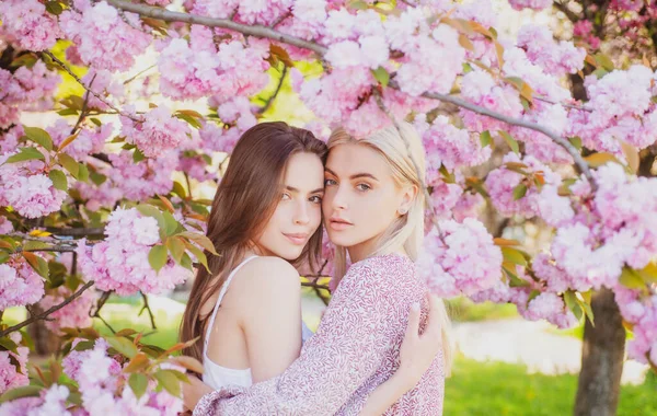 Två unga sensuella sexiga kvinnor som kopplar av i Sakura blommor. — Stockfoto