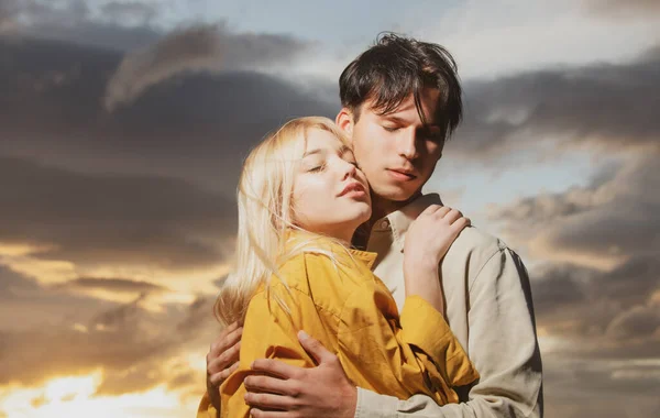 Retrato de casal encantador apaixonado no pôr do sol. Jovem namorada sensual feliz ao beijo apaixonado de seu namorado. Bonito jovem abraça sua mulher e beijos. — Fotografia de Stock