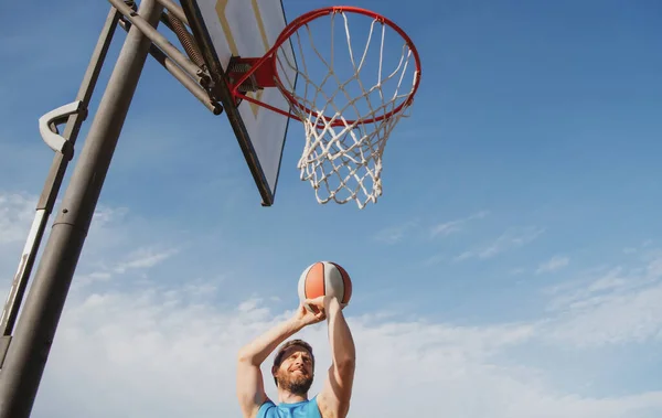 Sportovní muži hrají basketbal venku za slunečného dne. — Stock fotografie