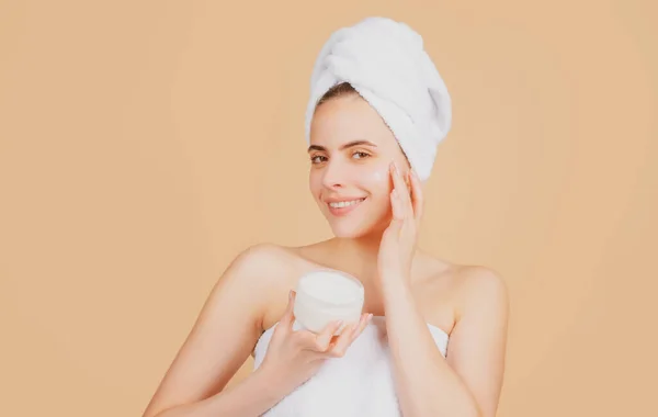 Schoonheidsvrouw met cosmetische producten schoon gezonde natuurlijke huid. Portret van een aantrekkelijk jong meisje met een badhanddoek op het hoofd. Mooie vrouw gezicht portret. — Stockfoto