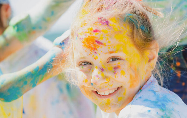 Child holi festival. Painted face of funny kid. Little girl plays with colors.