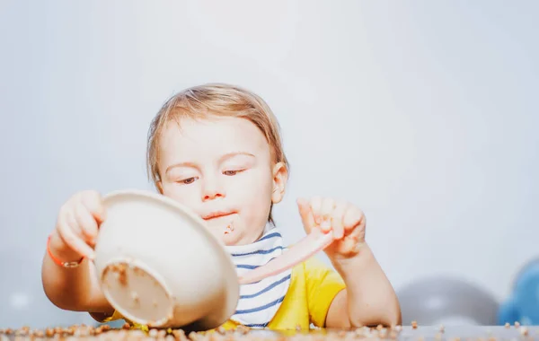 Baby kind eet voedsel. Grappige jongen met bord en lepel. — Stockfoto