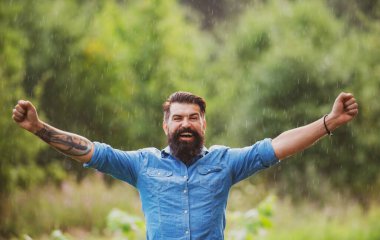 Fırtınalı yağmurlu hava konsepti. Su geçirmez giysi. Yağmur altındaki mutlu adam. Sonbahar havası.