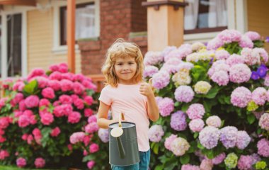 Çiçekleri sulama tenekesiyle sulayan tatlı çocuk..