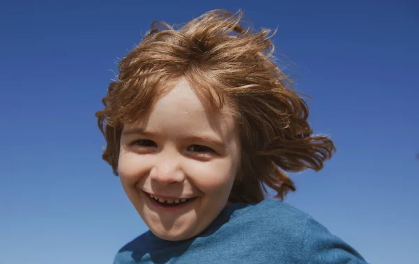 Porträtt av ett lyckligt skrattande barn på blå himmel med kopieringsutrymme. Närbild positiva barn ansikte. — Stockfoto