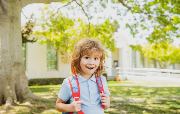 Elève de l'école primaire avec livre à la main. Écolier avec sac à dos près de l'école à l'extérieur. Début des leçons. — Photo