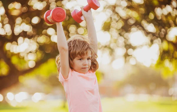 Çocuklar aktif, sağlıklı bir yaşam tarzı. Dambılı açık havada sportif bir çocuk. Çocuklar spor yapar. Çocuk parkta egzersiz yapıyor.. — Stok fotoğraf