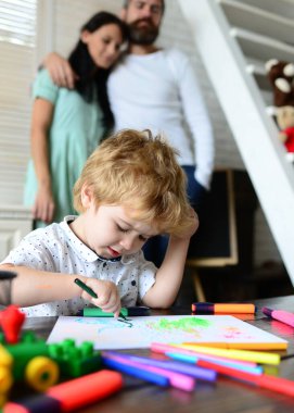 Mutlu aile eğleniyor, ebeveynler ve küçük çocuk birlikte oynuyor. Evde çizim yapan anne ve babası olan neşeli bir oğul. Çocuklu ebeveynler. Erken dönem sanat ve zanaat eğitimi, çizim.