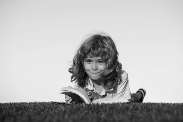 Imaginación de niños, niños soñando. Lindo niño leyendo libro sobre hierba verde. —  Fotos de Stock
