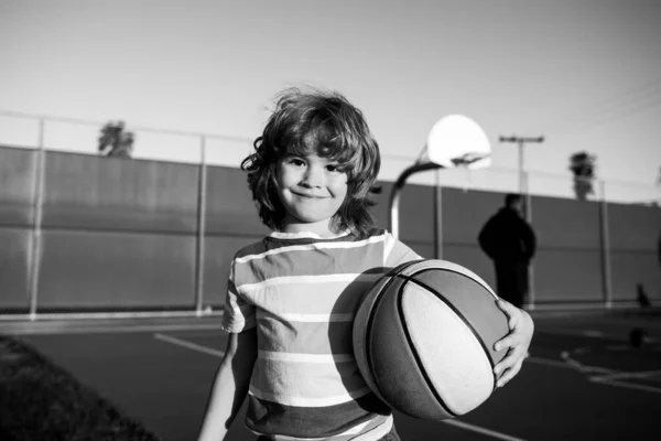 Pouco caucasiano esportes garoto jogando basquete segurando bola com rosto feliz. — Fotografia de Stock