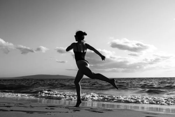 Femme courant sur la plage. Jeune fille en bonne santé courir à la plage du lever du soleil. — Photo